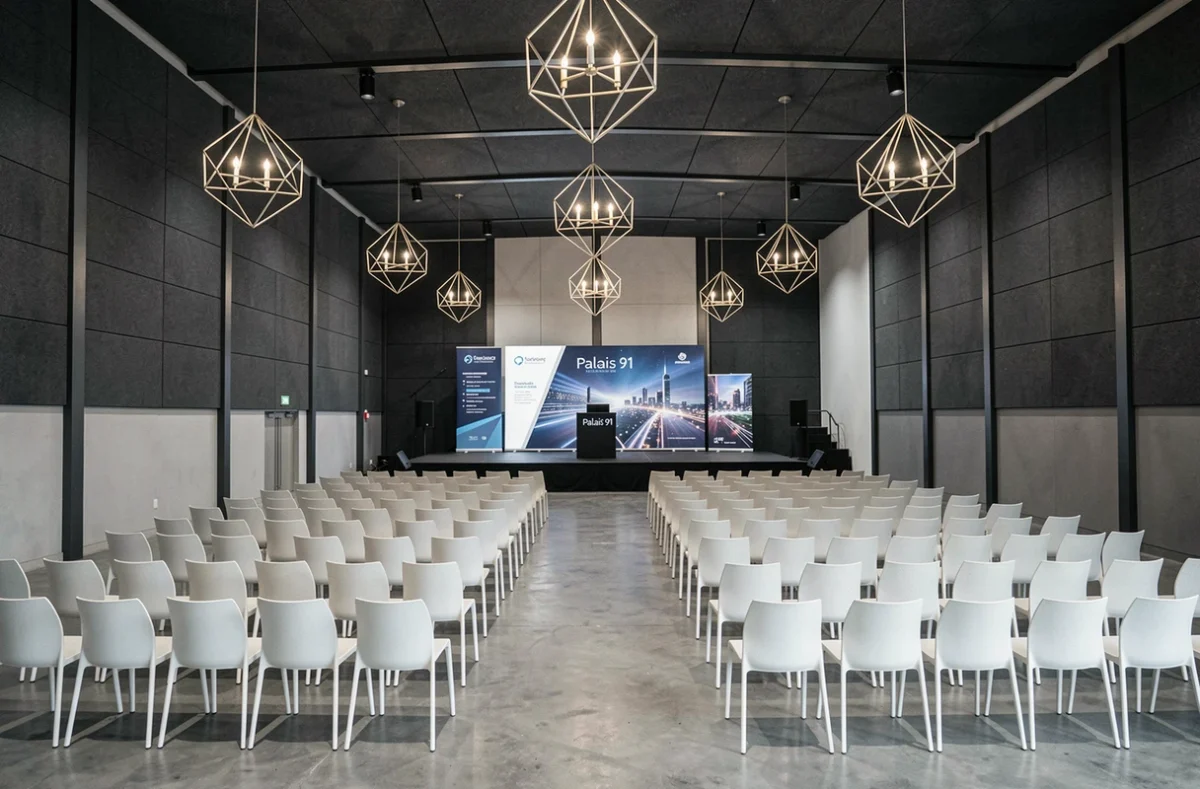 Grande salle modulable du Palais 91 en Essonne, aménagée pour un événement corporate avec scène et chaises modernes