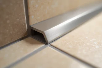 Profil de finition en inox brossé à l'angle d'un carrelage mural et sol dans une salle de bain moderne